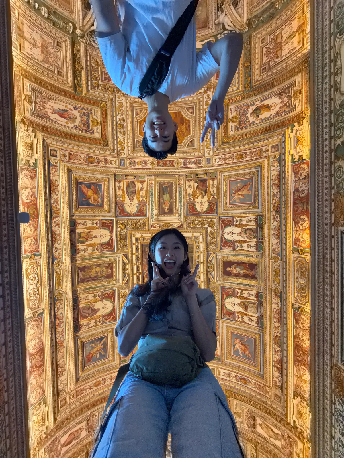 Two visitors under a painted and gilded ceiling in the Vatican Museums in Rome
