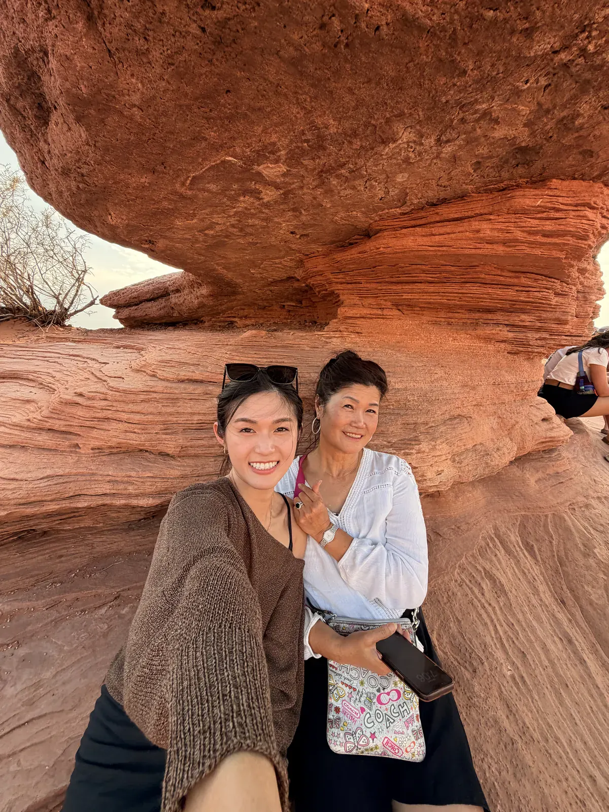Two visitors sitting beneath a layered red sandstone overhang at Red Rock Canyon outside Las Vegas