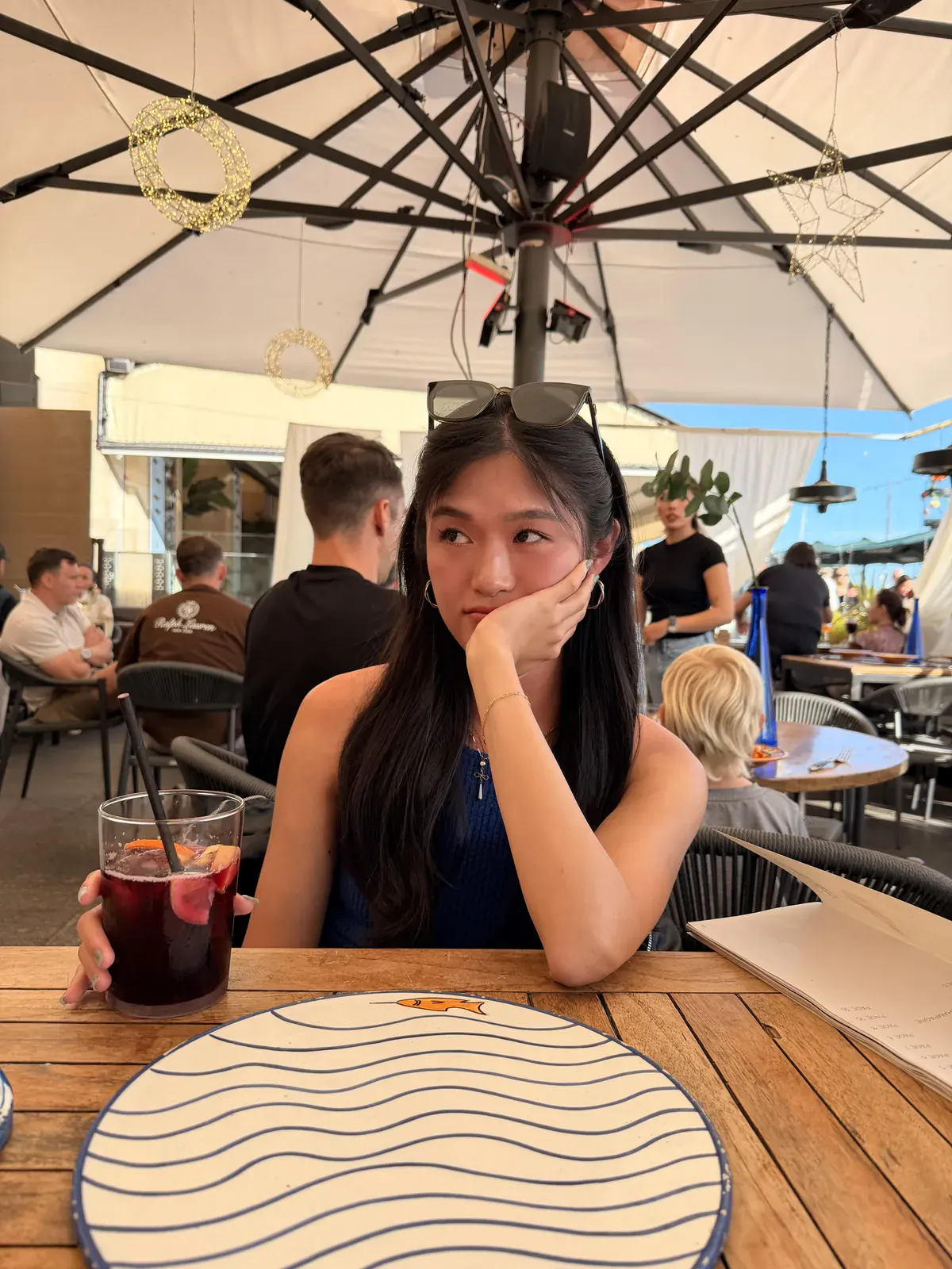 A woman holding a glass of sangria at an outdoor restaurant terrace in Barcelona.