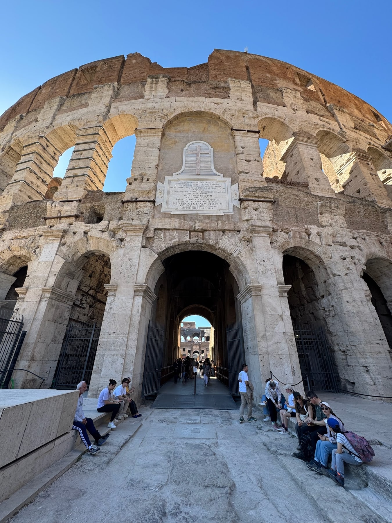 Visitors walking beneath a monumental interior arch at the Colosseum