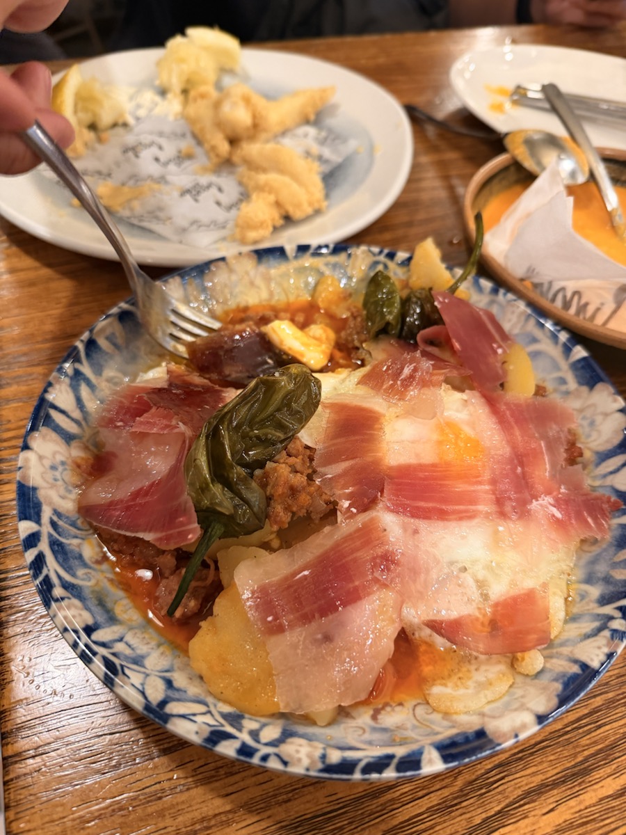 A Seville tapas plate with jamón, egg, potatoes, and peppers