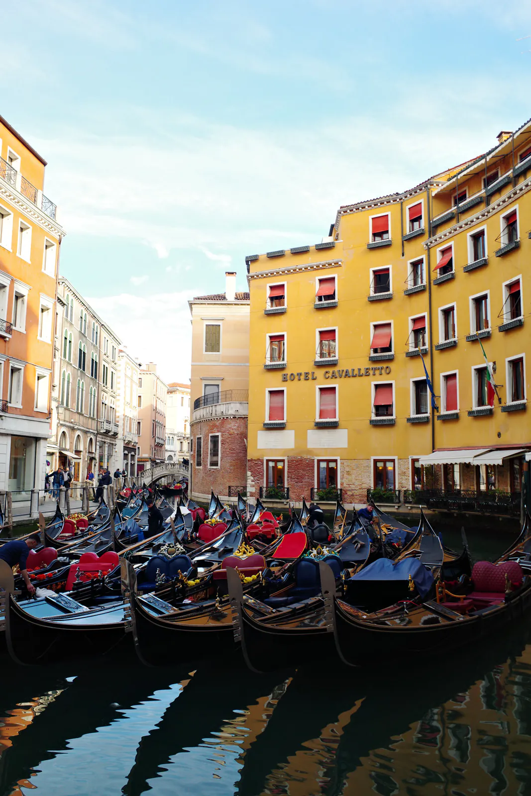 Rows of gondolas waiting along a colorful side canal in Venice