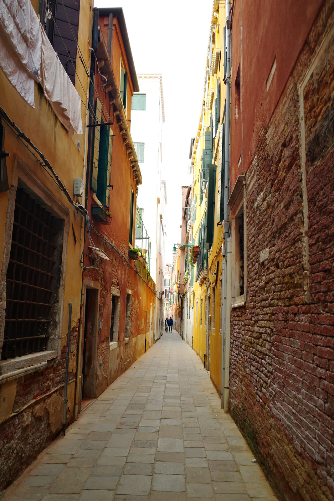 Narrow brick alleyway between colorful buildings in Venice