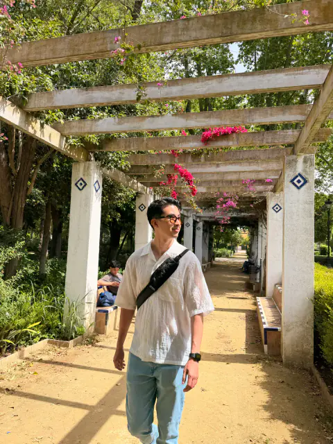 Walking beneath a flower-covered pergola in Parque de María Luisa in Seville